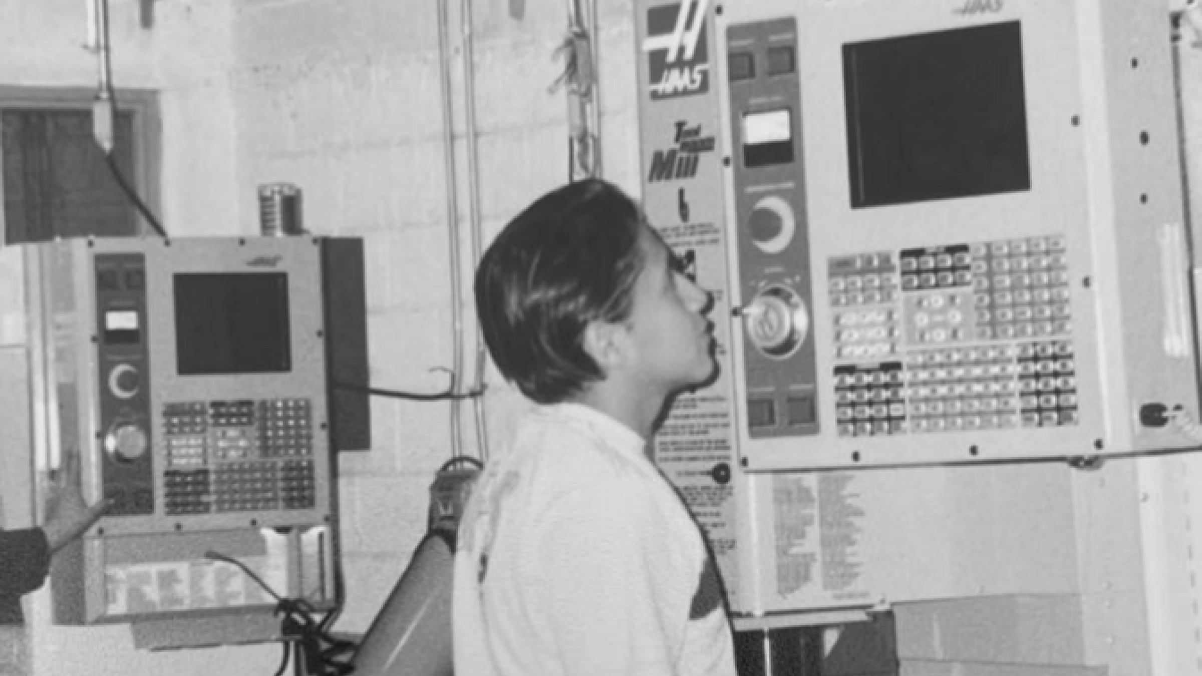 Omar at 13 looking up at his father's first CNC machine